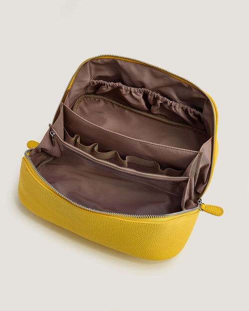 Interior view of a leather layflat vanity bag in yellow, showcasing zippered and open pockets for organization.