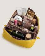 Leather layflat vanity bag filled with beauty products and cosmetics, showcasing interior compartments and organization.