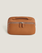 LayFlat Vanity Bag in tan full grain leather with zip-around closure and handle.