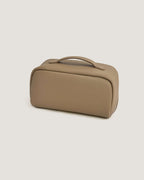 LayFlat leather vanity bag in beige, crafted from full grain leather with a sleek, rounded design.