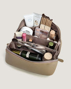 Inside view of a layflat leather vanity bag filled with cosmetics and beauty tools.