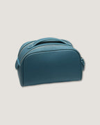 Teal leather makeup bag with double-zipper design and durable textured exterior.