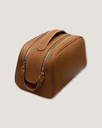 Leather makeup bag in tan color with double zippers and a soft texture, perfect for organizing cosmetics.