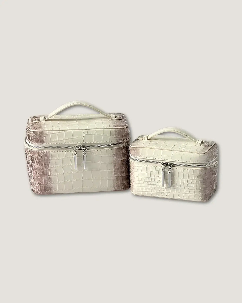 Large leather train case and small leather train case in cream color with crocodile pattern.