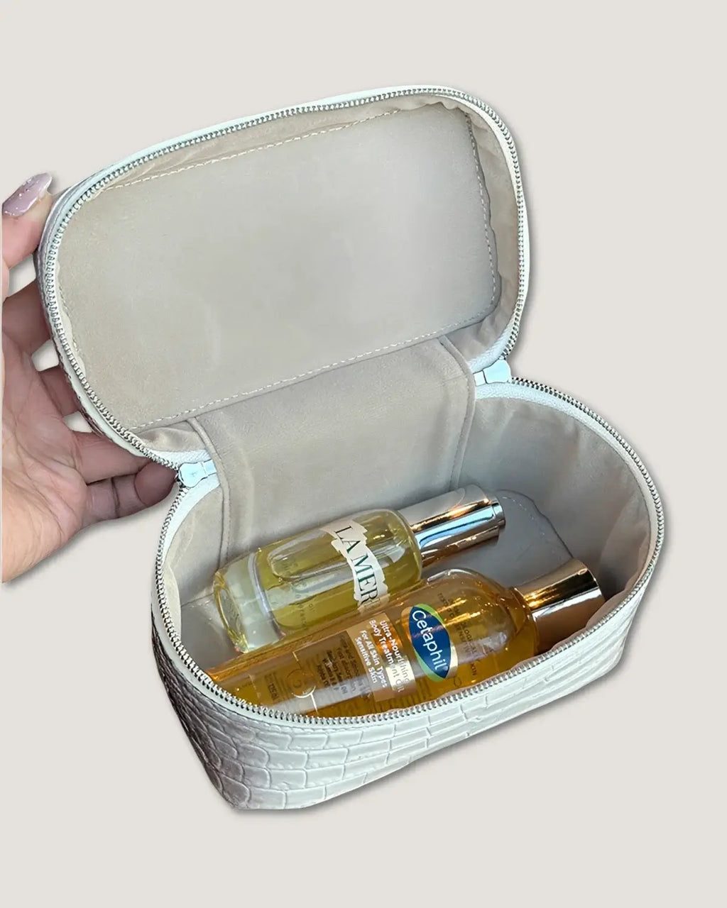 Interior view of a large leather train case with cosmetic bottles inside.