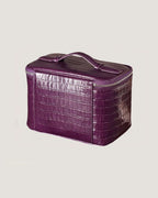Medium leather train case in purple croc texture with zippered closure and flat top handle.