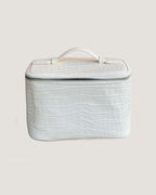 Medium leather train case made of white textured Italian leather with zip closure and top handle.