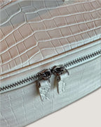 Close-up of a white medium train case with Italian leather featuring a metal zip-around closure.