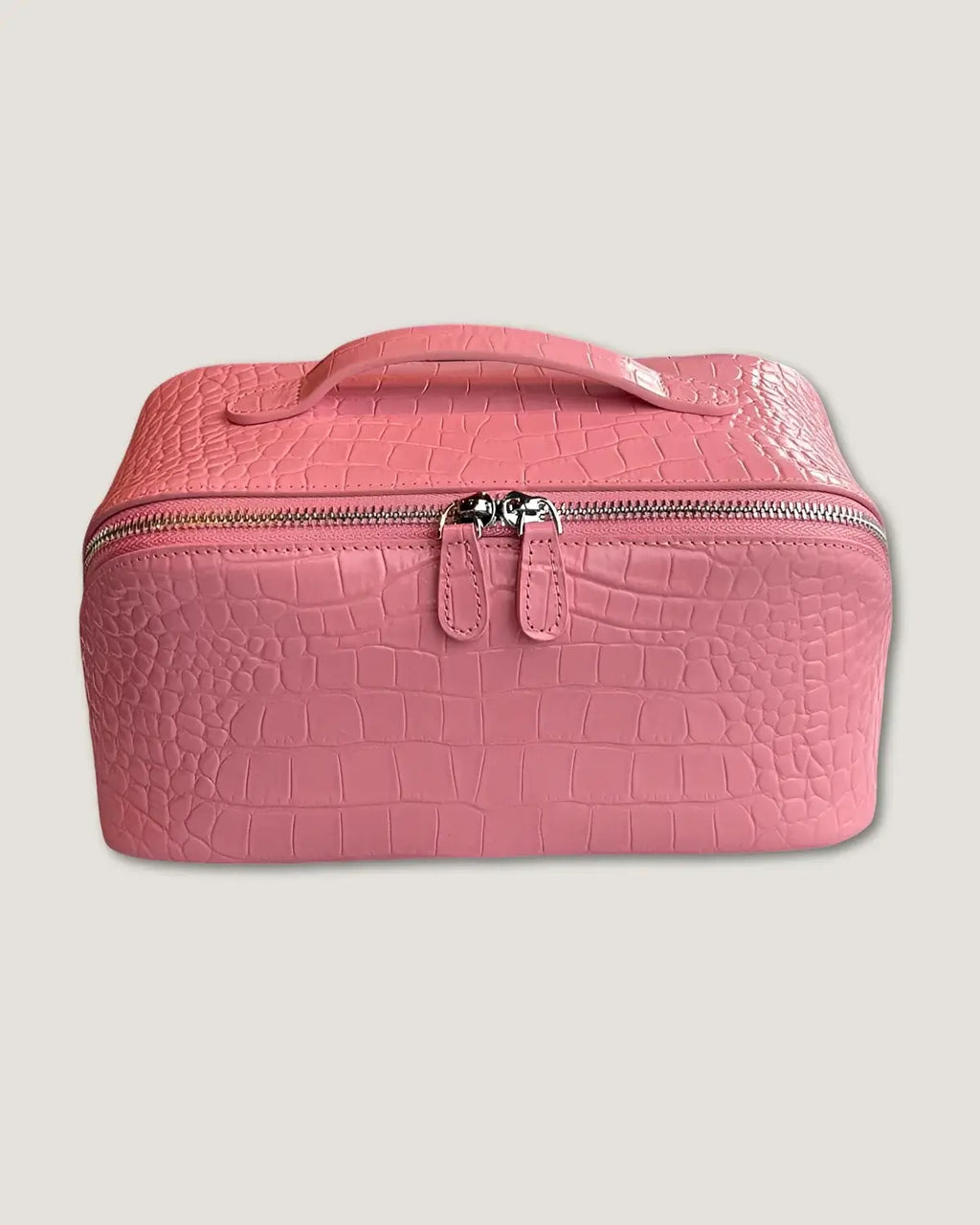 Layflat leather vanity bag in crocodile pattern pink with zip-around closure and handle.