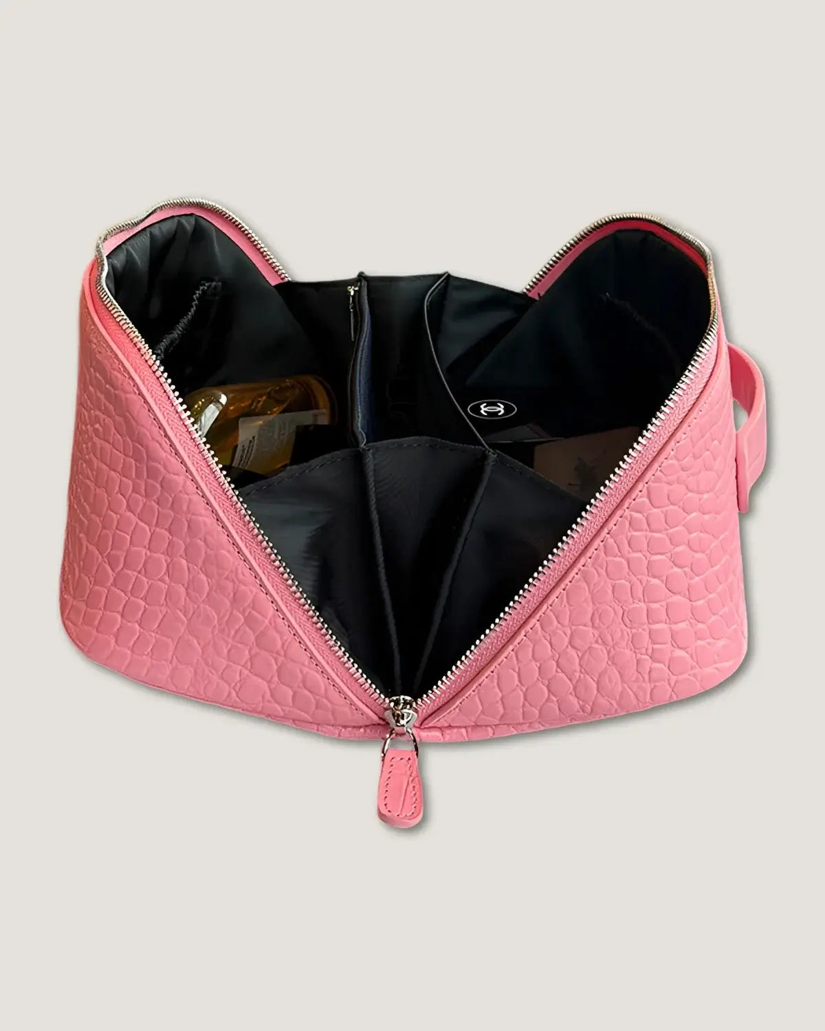 Inside view of a pink layflat leather vanity bag featuring multiple pockets and a zip-around closure.