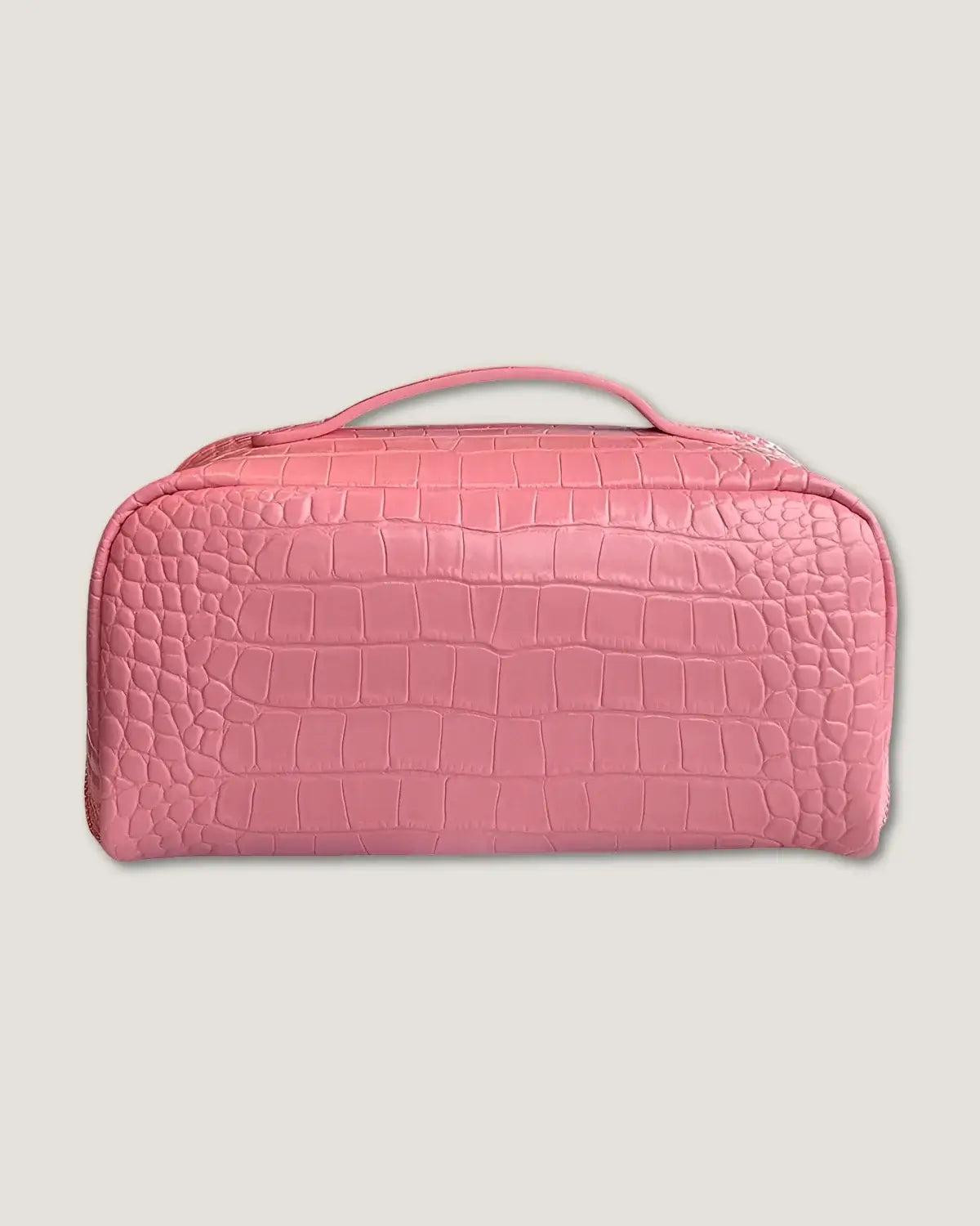 Layflat leather vanity bag in pink crocodile pattern with zip-around closure and handle.