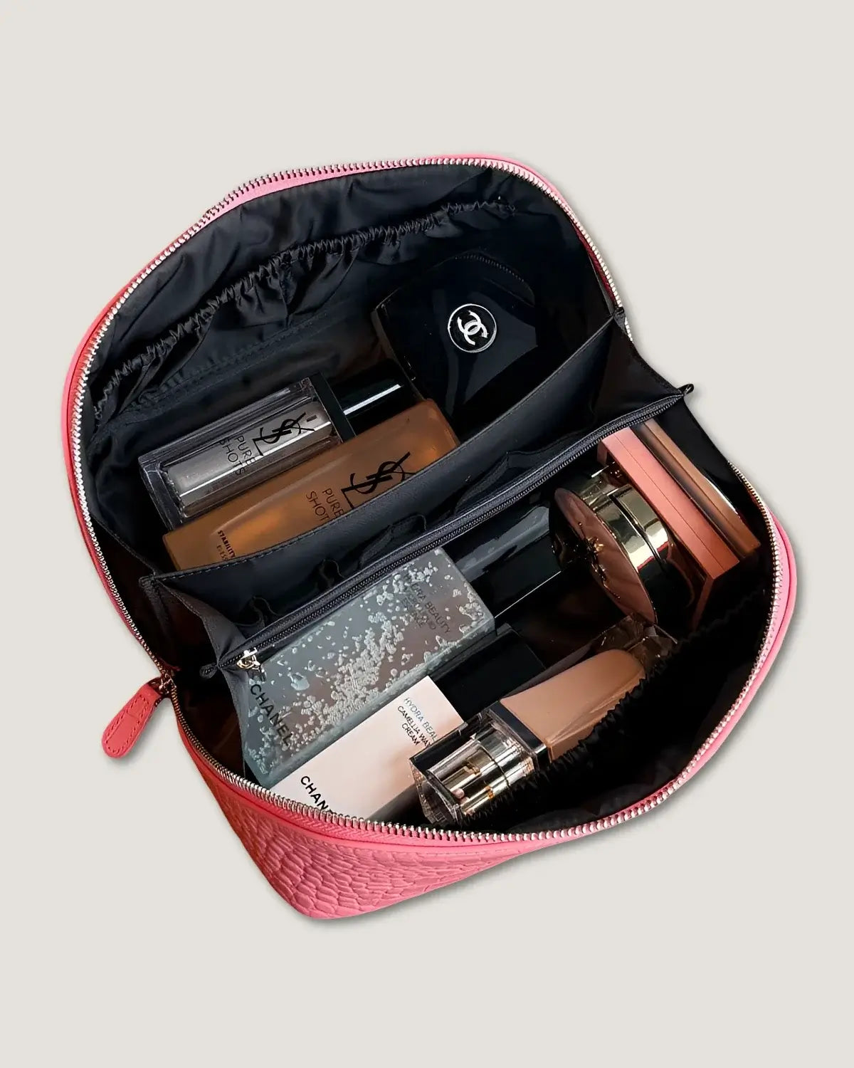 Inside view of a layflat leather vanity bag filled with makeup products and bottles.