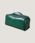 layflat leather vanity bag in glossy green crocodile pattern with zippered closure and handle