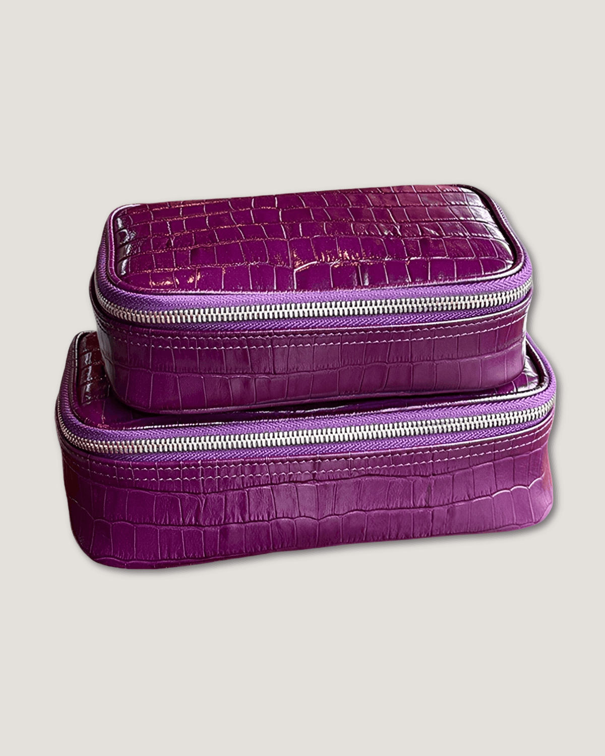 Large rectangular leather makeup bag in crocodile patterned sea anemone with zip-around closure.