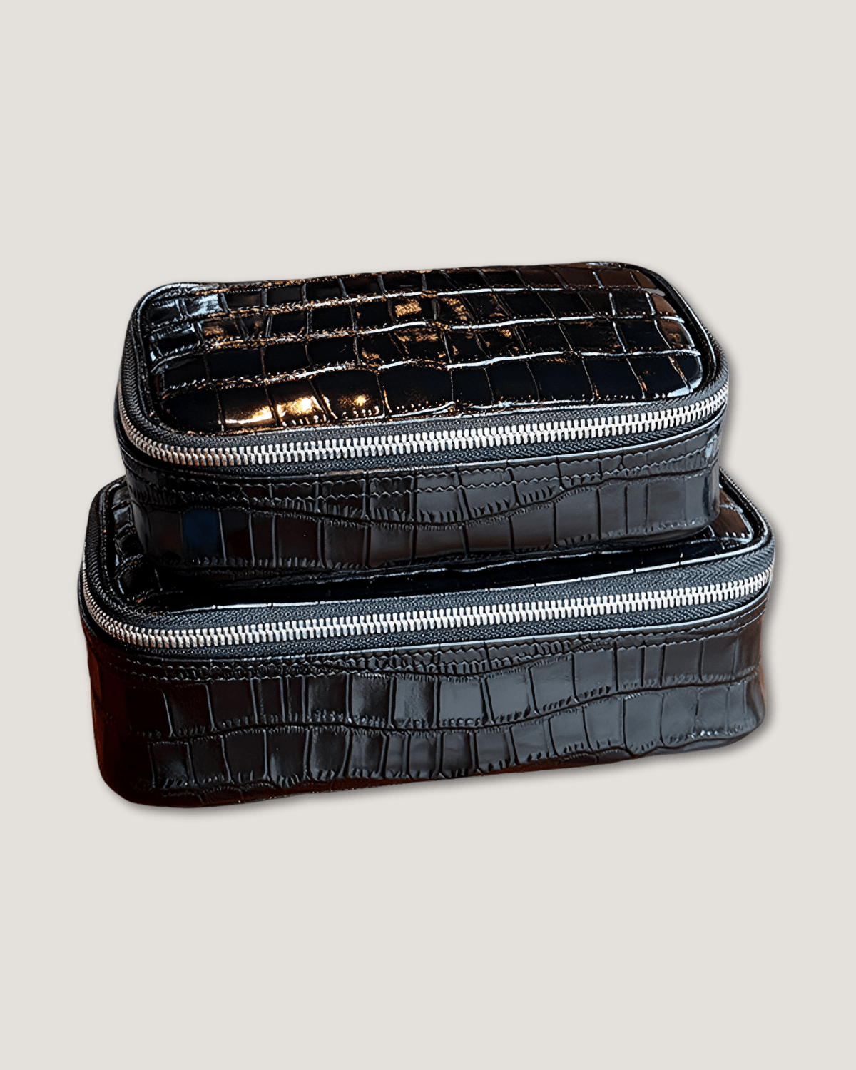Large rectangular leather makeup bag in crocodile pattern black with metal zip-around closure.