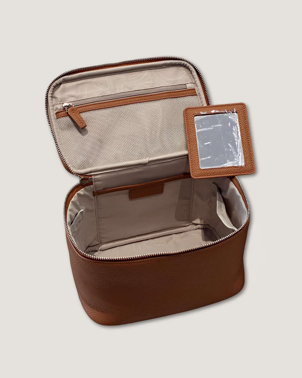 Medium leather vanity bag interior view with zippered pocket and mirror.