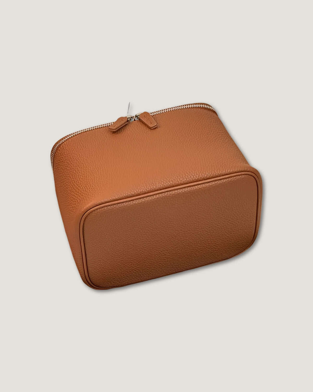 Medium leather vanity bag in tan leather with metal zip closure on a neutral background.