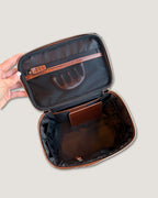 Inside view of a leather train case showing zippered and open pockets.