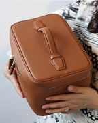 XL leather train case held by a person showcasing its full grain leather and stylish design.