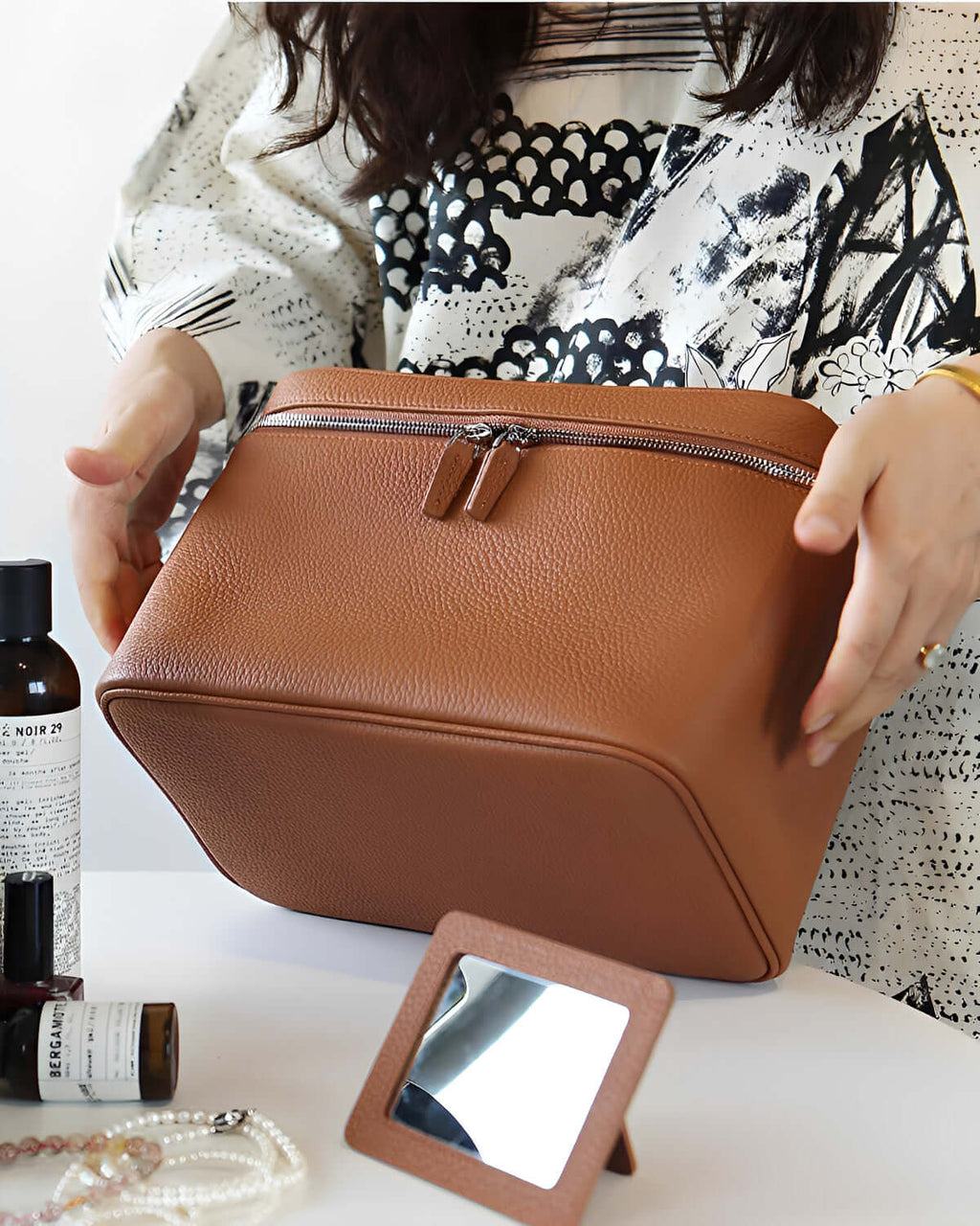 XL leather train case being held by a person, showcasing its full grain leather finish and stylish design.