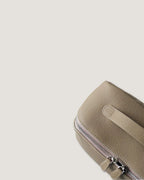 Close-up of a layflat vanity bag showcasing its textured leather and metal zip closure.